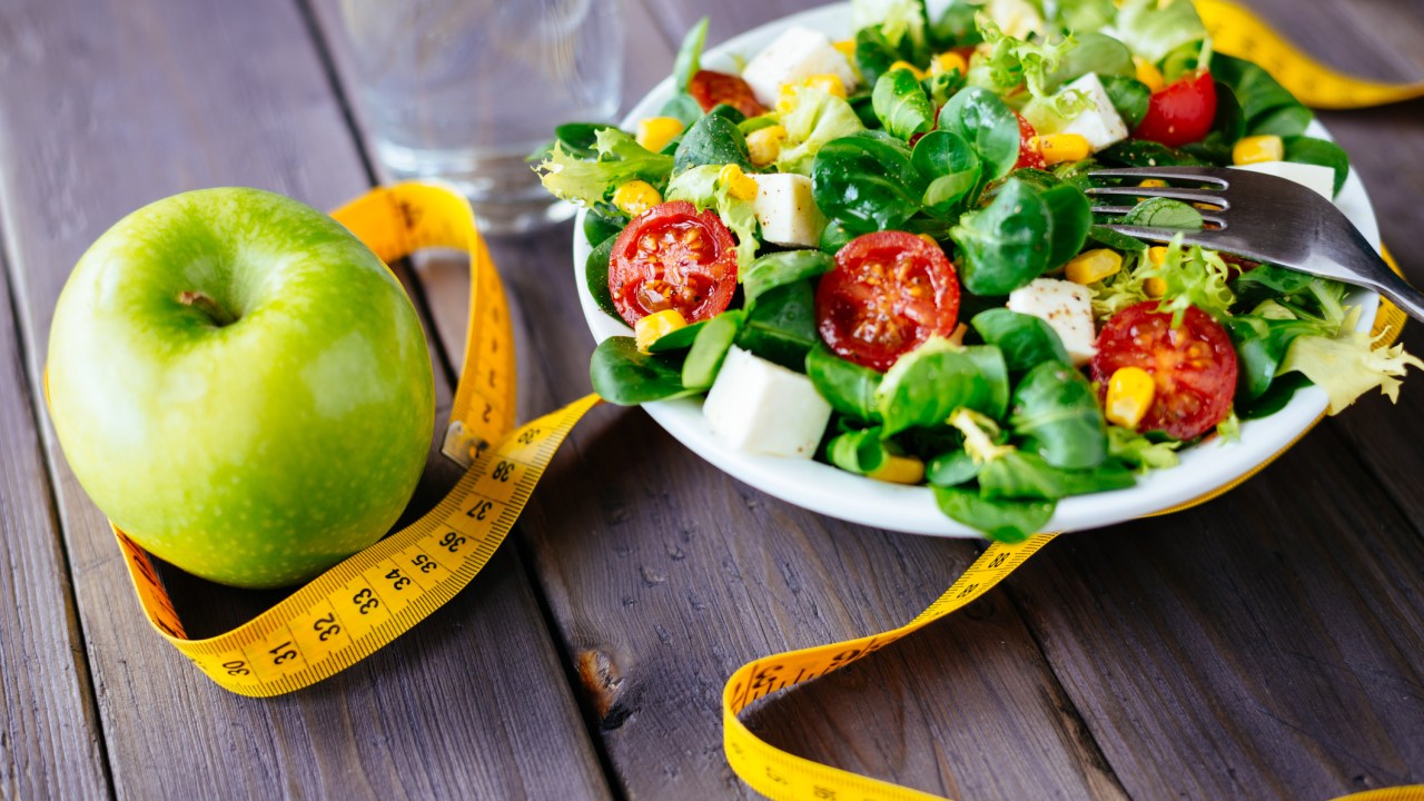 Prato de salada, fruta e fita métrica