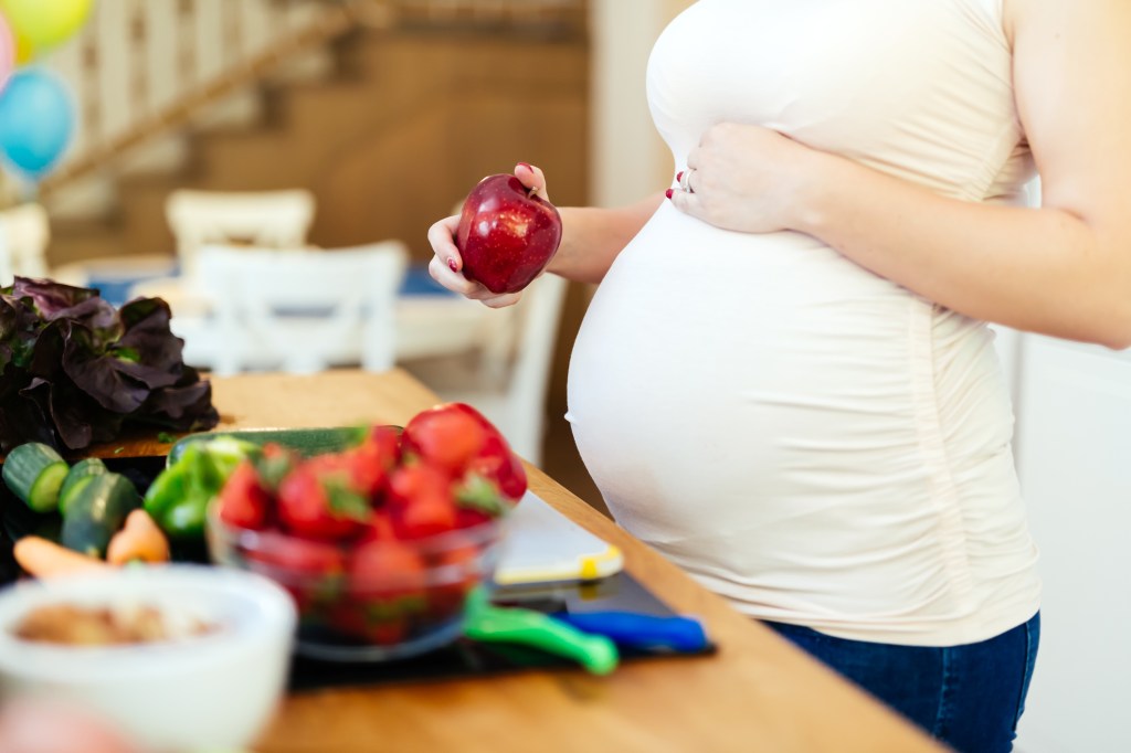 Mulher grávida comendo frutas, como maçã