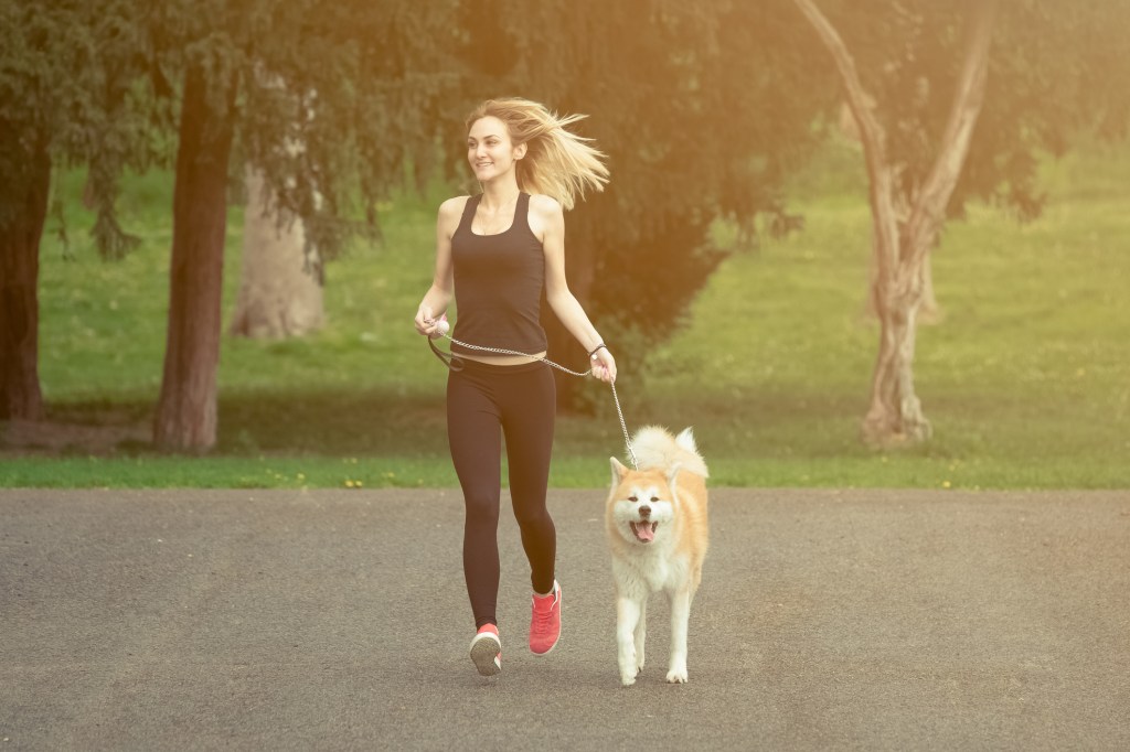 Mulher com roupa de ginástica correndo com cachorro