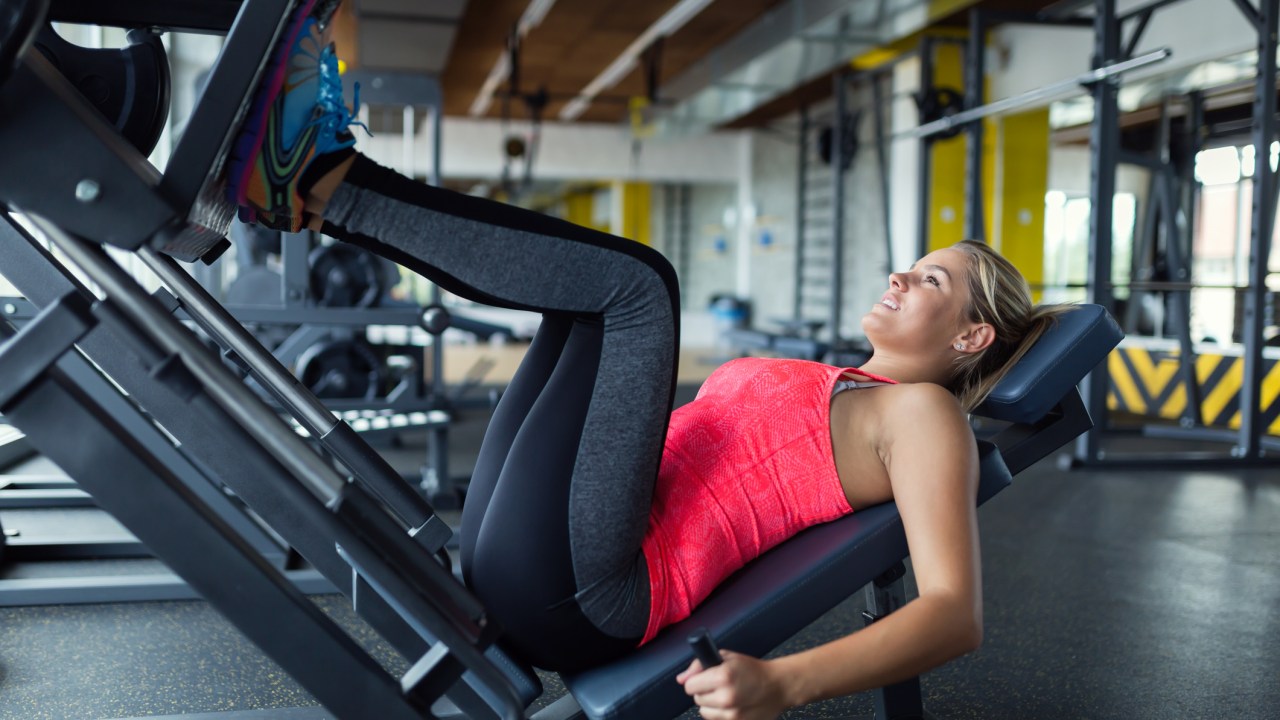 Mulher fazendo leg press na academia