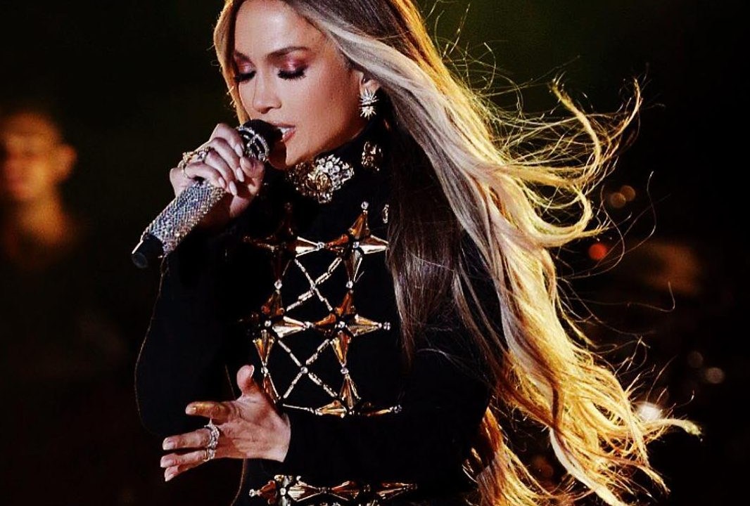Cantora Jennifer Lopez com o cabelo loiro cantando no palco