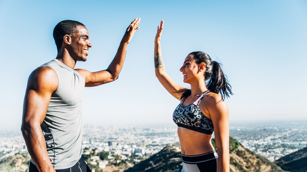 Homem e mulher praticantes de corrida comemorando após concluir exercício