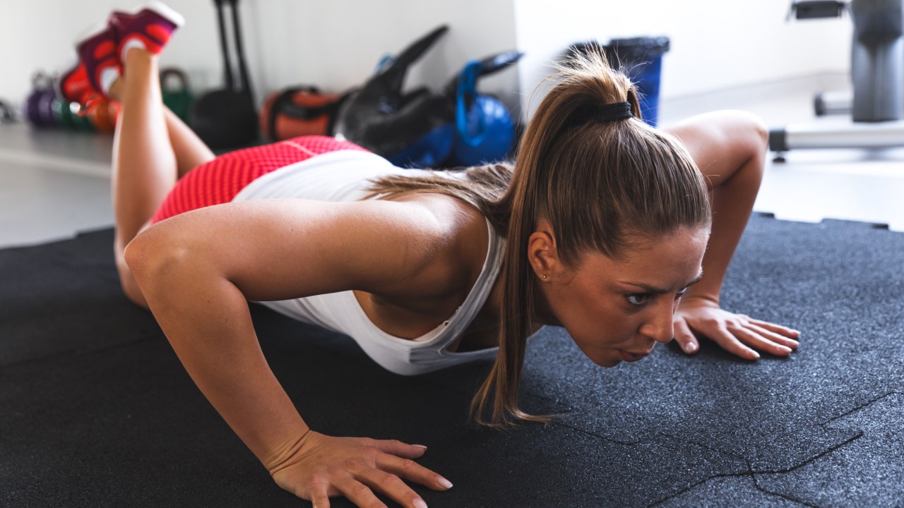 mulher fazendo flexão de braços na academia