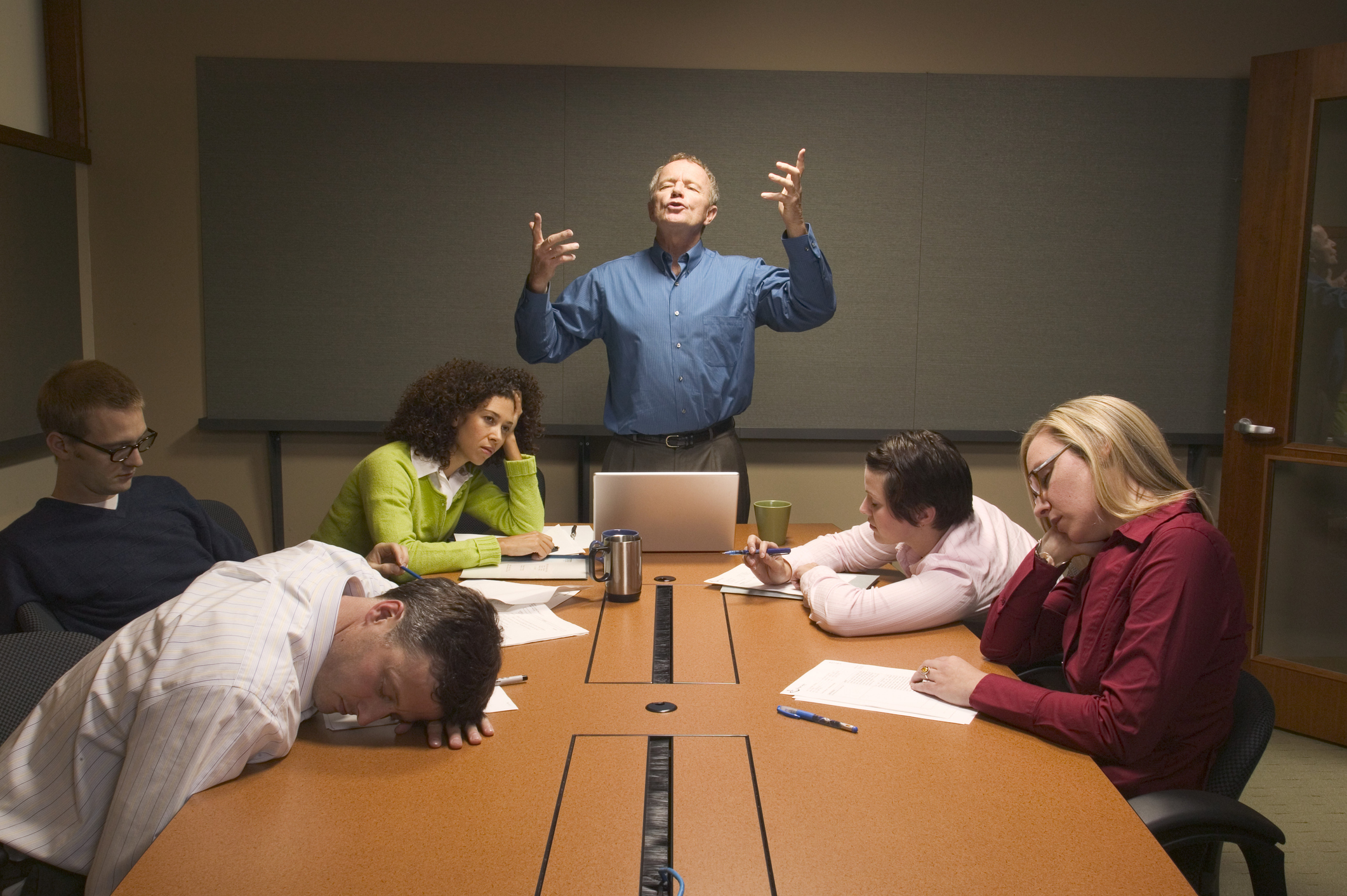 Businessman speaking before inattentive colleagues at meeting -