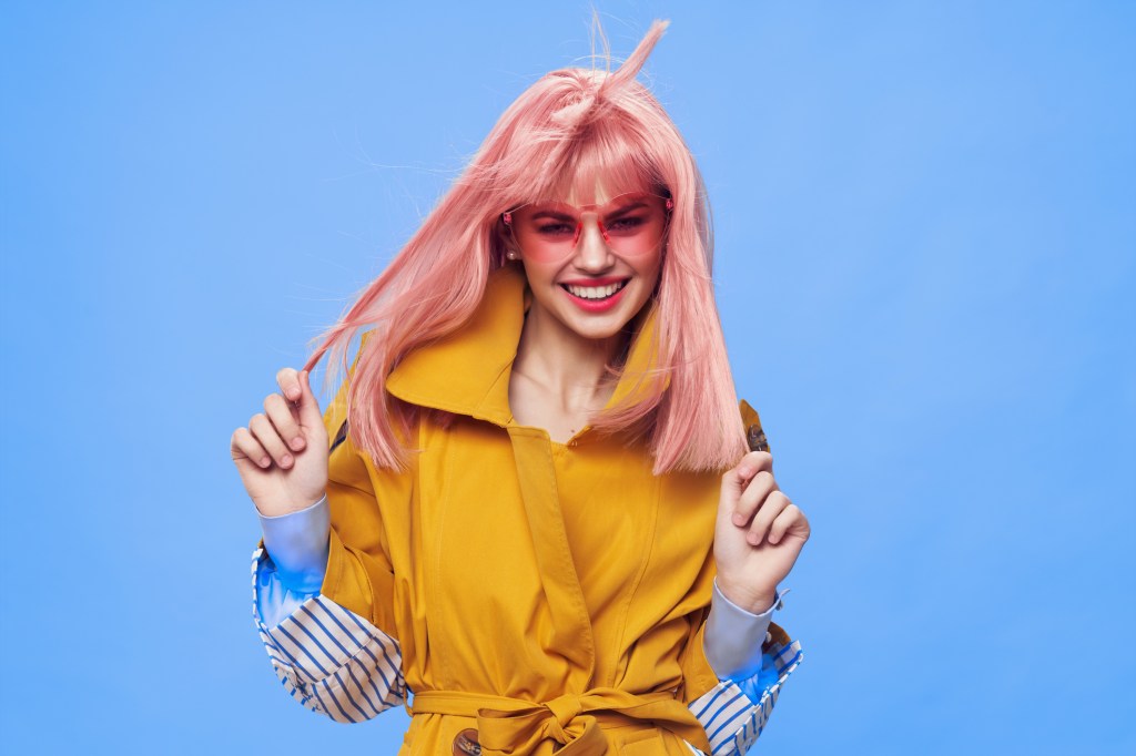 A fashionable woman in a pink-cloak coat dyed her hair and is pleased with her new look. -