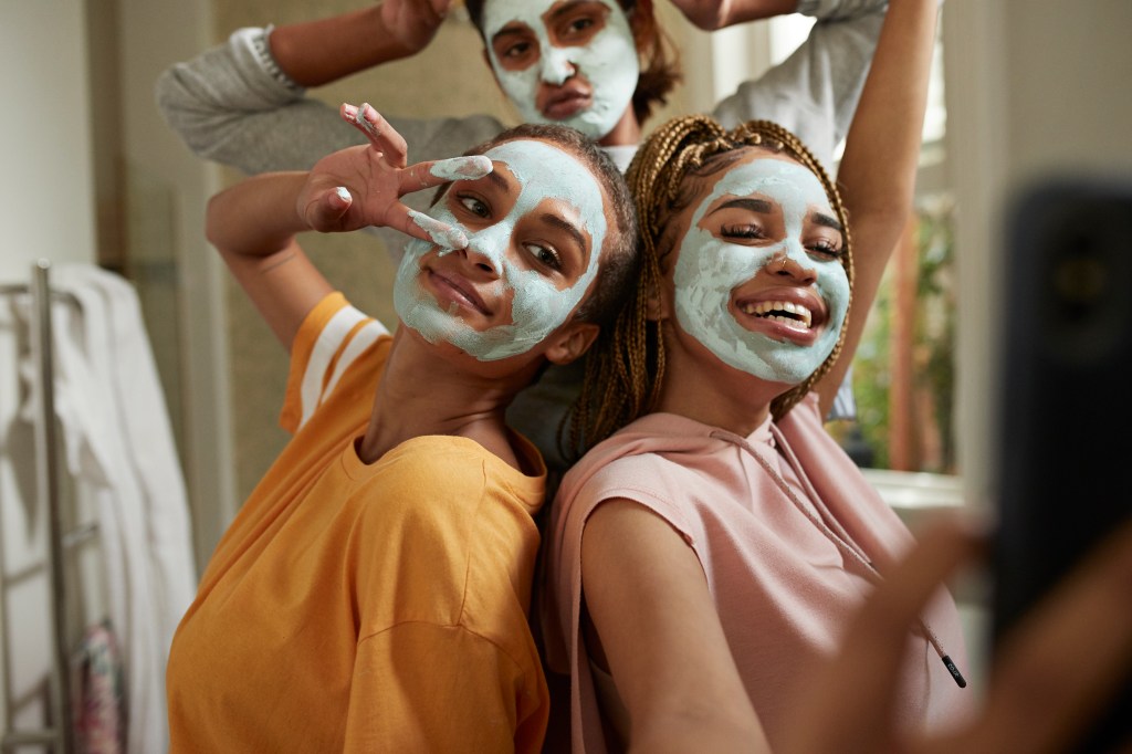 Happy woman taking selfie with friends wearing cream mulheres de mascara