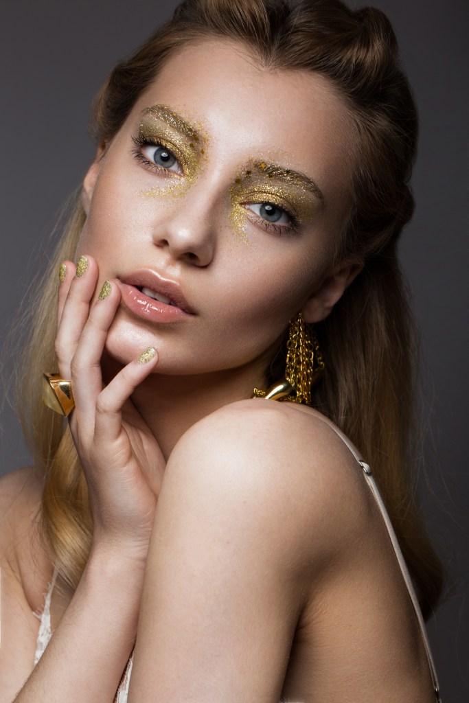 Beautiful girl in Underwear with creative gold makeup and hair. -