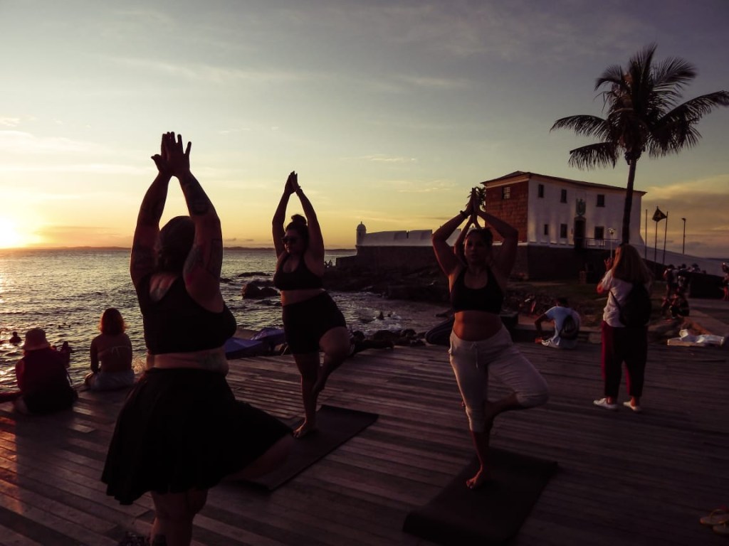 Mulheres gordas fazendo yoga ao ar livre, no pôr-do-sol