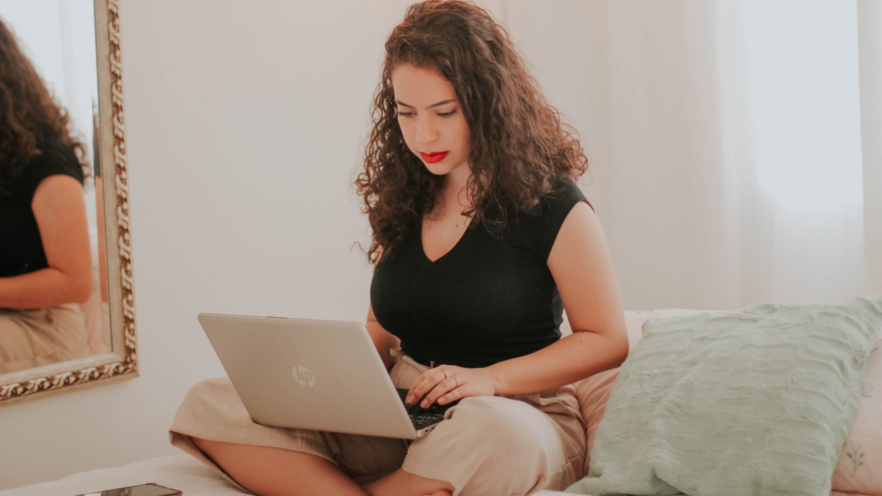 mulher trabalhando de casa, com o computador no colo
