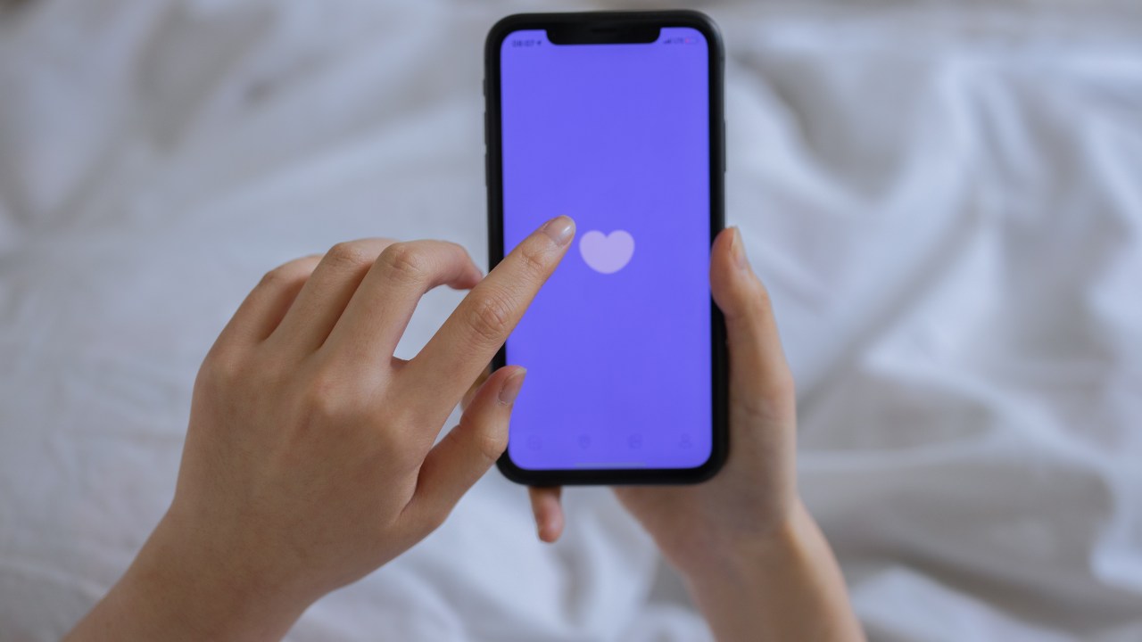 mulher segurando o celular com um coração na tela