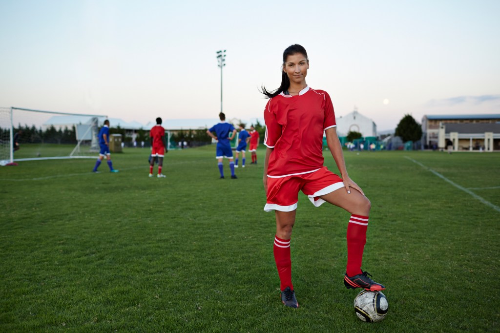 Female soccerplayer standing with foot on the ball Female soccerplayer standing with foot on the ball