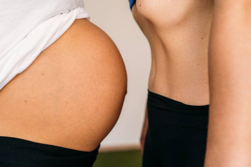 Close-up of  Sporty young woman doing hypopressive abdominal with a pregnant.