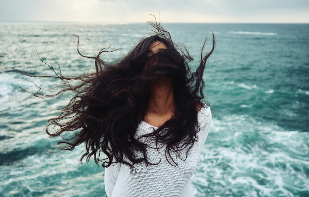 mulher com cabelo sobre o rosto, mar ao fundo