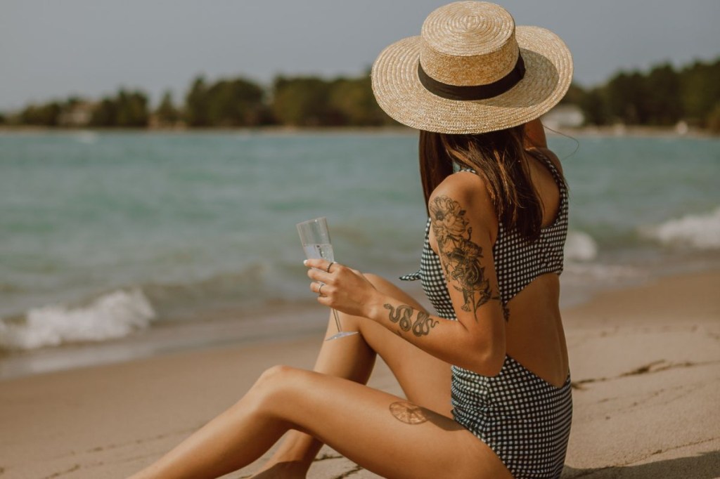 verão-cuidados-pele (9) Mulher de chapéu e tatuagem na praia