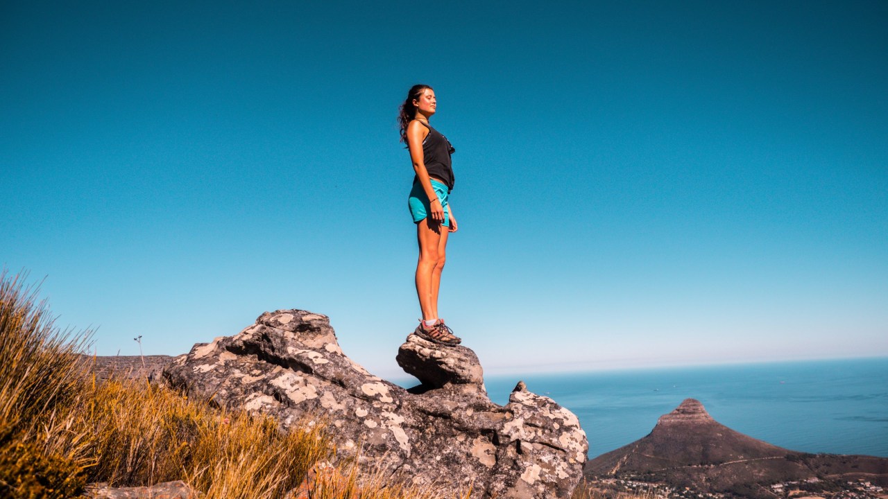 Mulher de pé no alto de uma pedra