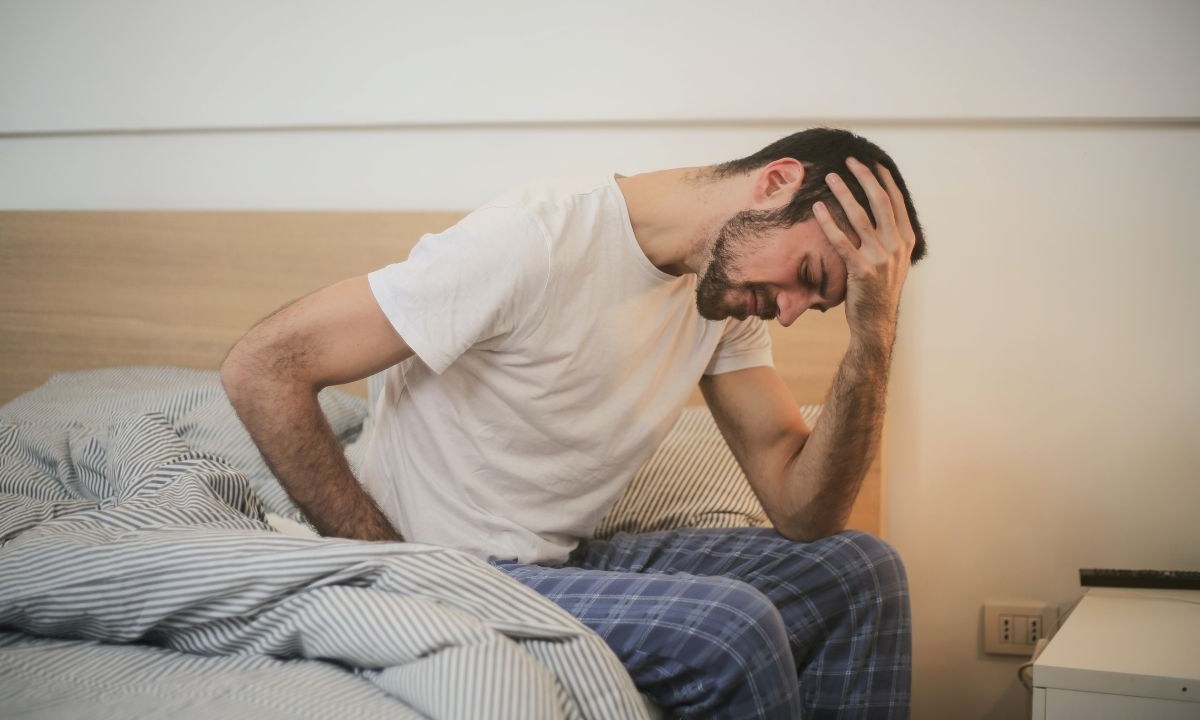 Homem com enxaqueca sentado na cama