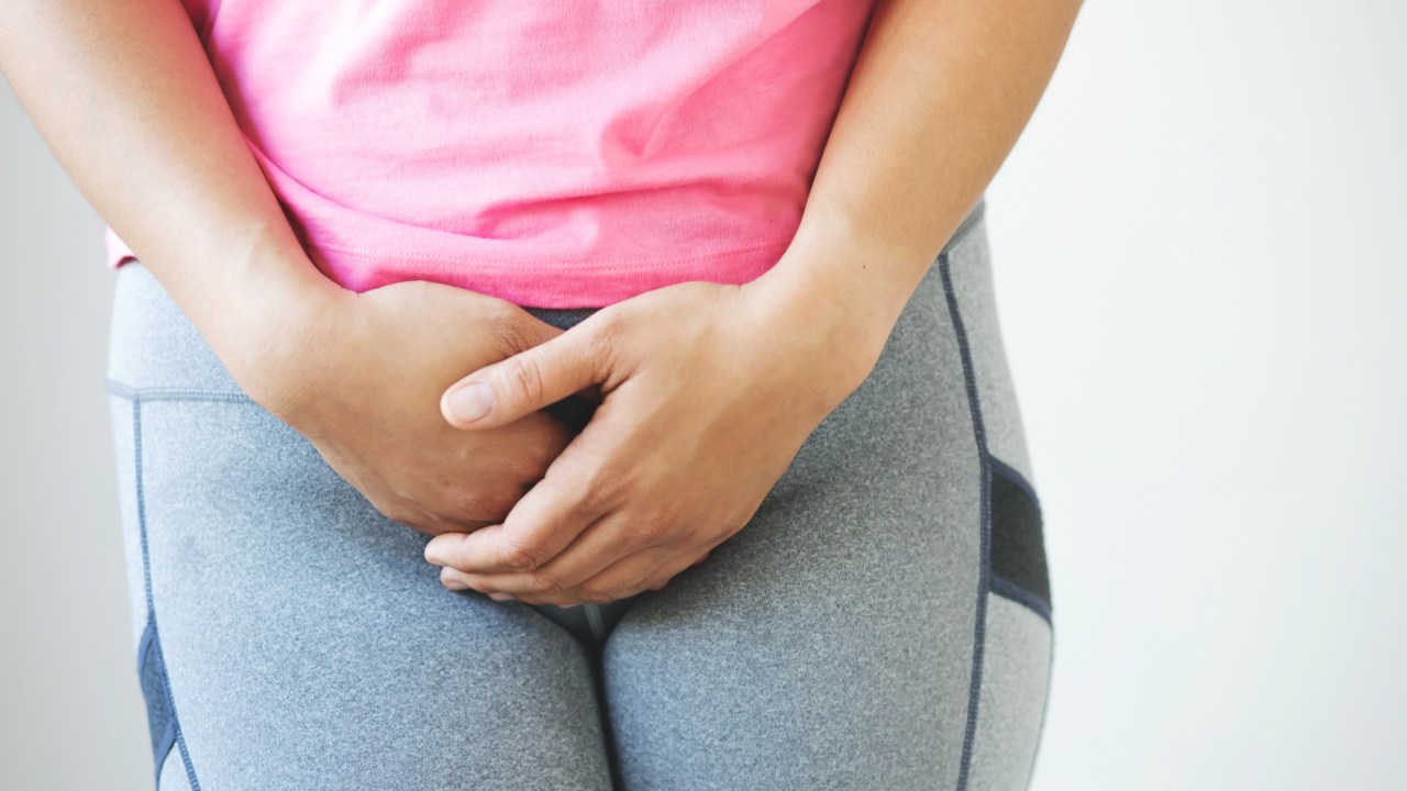 mulher de roupa de ginastica segurando a vagina, como se sentisse dor | dores íntimas